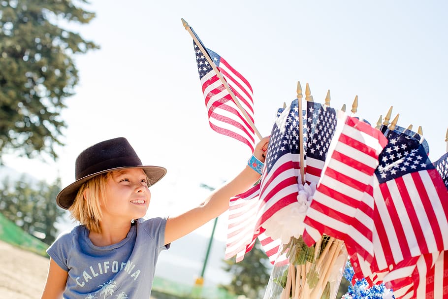 Photo of child reaching for a US flag for post about Independence Day 2023 - Toward a more perfect union